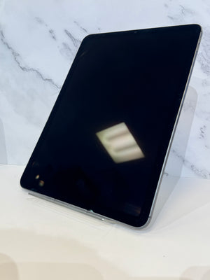 A black tablet with a silver edge, shown at an angle on a clear stand against a white marble-patterned background.