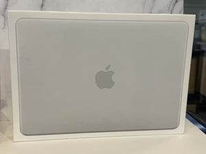 A closed silver Apple laptop, likely a MacBook, sitting inside its white retail box. The Apple logo is visible in the center of the lid.