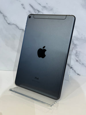 A dark gray Apple iPad shown from the back, standing upright on a clear acrylic display stand against a white marble-patterned background.