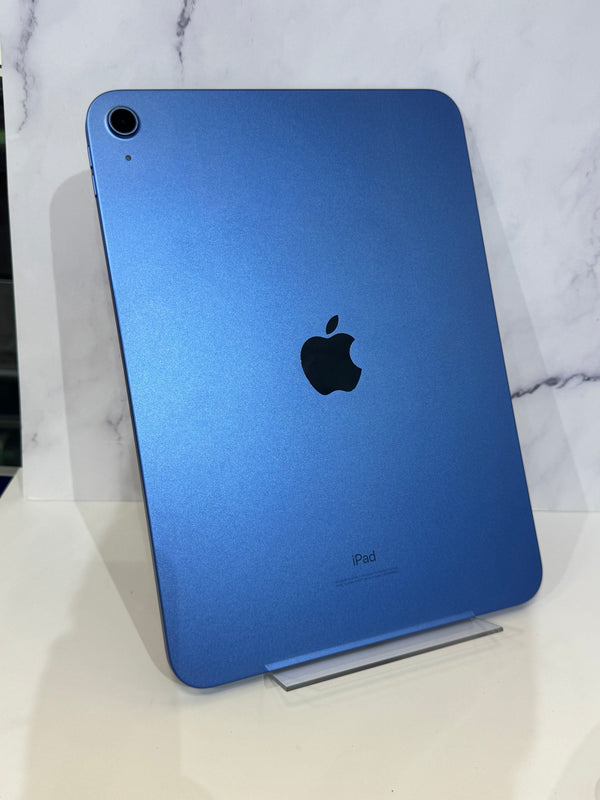A blue Apple iPad shown from the back, standing on a clear acrylic display block against a white marble-patterned background.