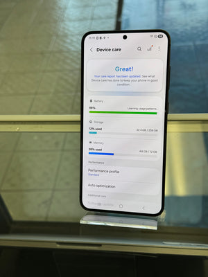 Smartphone displaying a device care app on a reflective glass surface