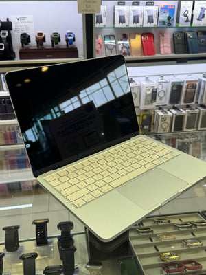 A silver Apple iPad with a light beige keyboard cover and trackpad, shown open on a display stand inside a retail store.