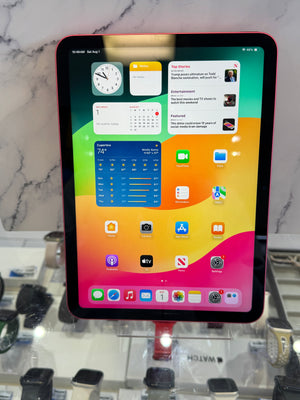 A tablet device with a colorful gradient home screen, resting on a white marble surface with a watch display visible in the background.