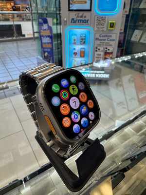 Smartwatch with colorful app icons on a reflective surface, with a store interior in the background.
