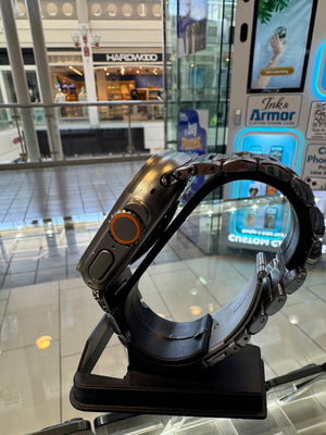 Apple watch with a black wrist strap on a stand in a mall setting