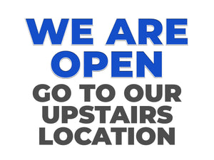 Text sign indicating "We are open, go to our upstairs location"