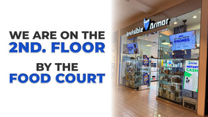 Store entrance with 'Invisible Armor' branding and promotional signs, with text indicating location on 2nd floor by food court.